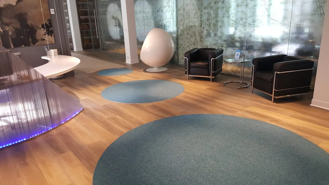 Accueil de bureaux avec fauteuils cuir, tapis ronds et parois vitrées décorées