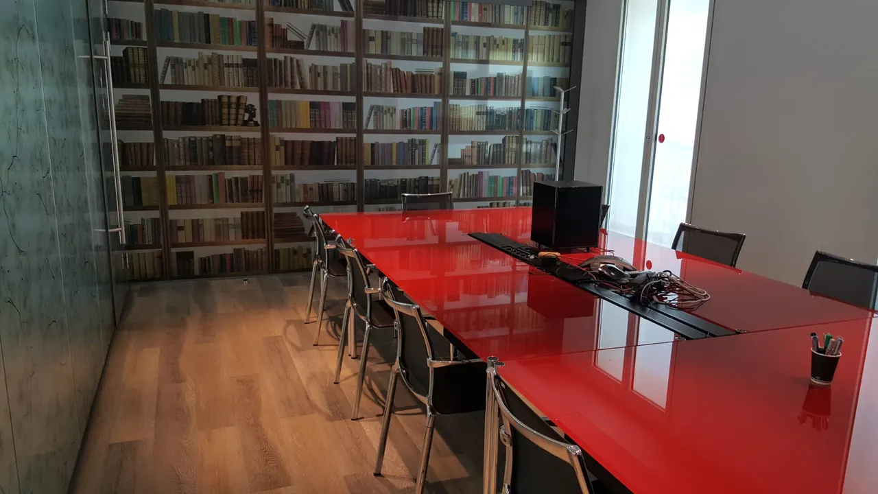 Salle de réunion avec table laquée rouge et papier peint bibliothèque
