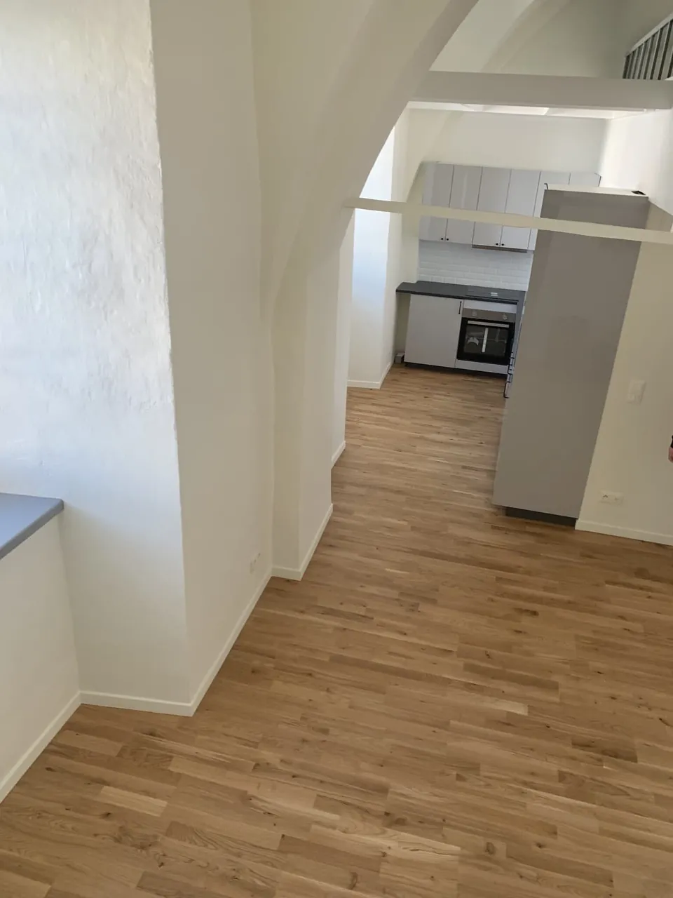 Cuisine blanche ouverte sur séjour avec parquet