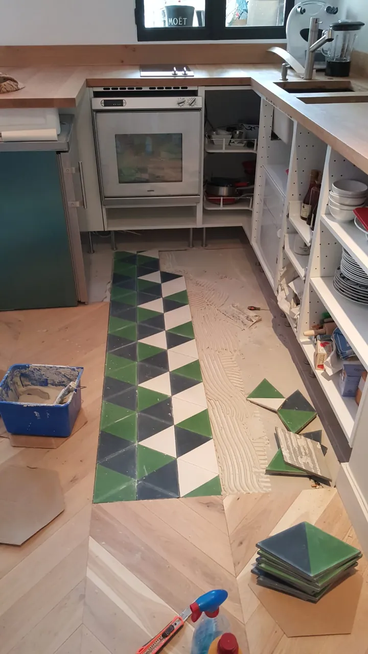 Pose de carreaux de ciment géométriques sur un chantier de cuisine