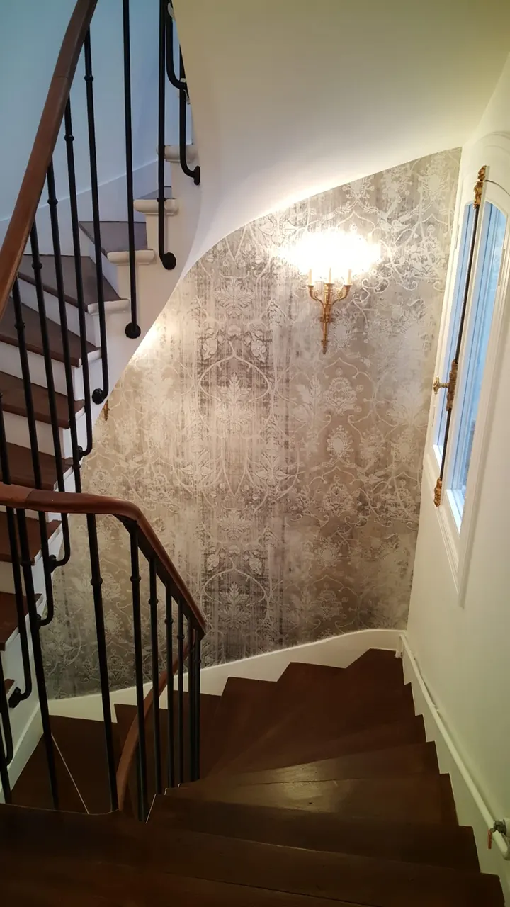 Escalier tournant avec papier peint texturé et applique dorée